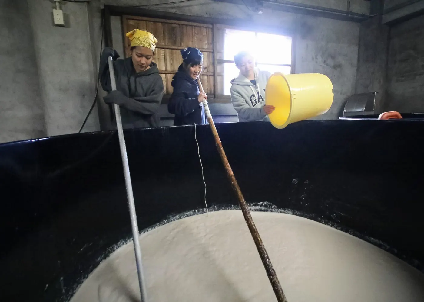 在酒槽邊攪拌酒醪的釀造現場
