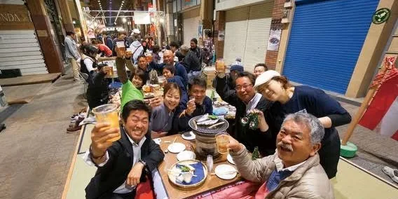 商店街裡擺開宴席,大家坐在榻榻米上舉杯乾杯